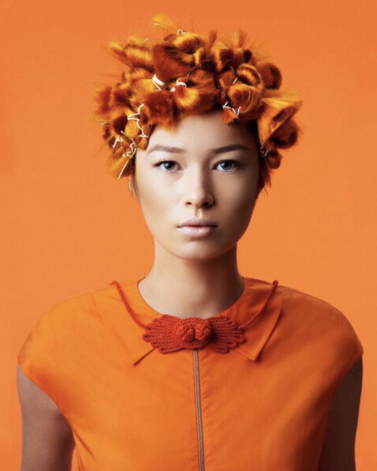 Woman with stylish, orange haircut set on an orange background